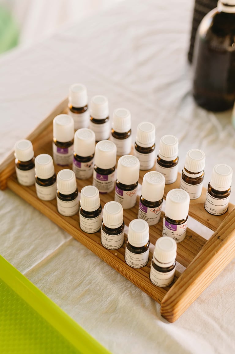 Collection of small glass bottles with dropper caps organized on a wooden tray, containing various essential oils or serums with purple and black labels.