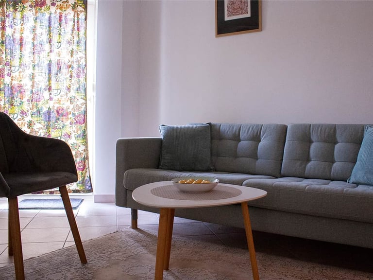 Modern living room with gray sectional sofa, wooden coffee table, black mid-century chair, and floral curtains by window